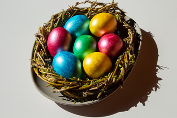 Colorful easter eggs in nest on white background with shadow.