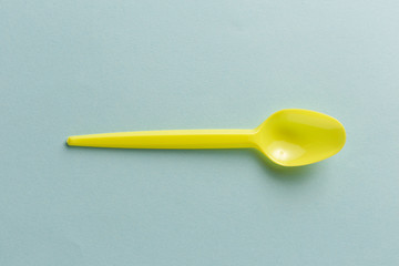 Yellow plastic spoon on a blue background.