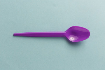 Violet plastic spoon on a blue background.