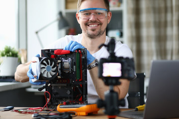 Man sits at table and repairs computer processor. Replacement with proven components from manufacturer or installation purchased device. Guy rejoices over repair during quarantine self-isolation