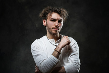 Close-up portrait of a young handsome male model posing on a grey background in a dark studio,...