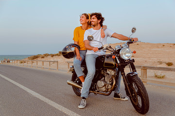 young couple on motorcycle on a road traveling to the beach