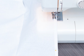 White sewing machine with white cotton fabric, close-up.