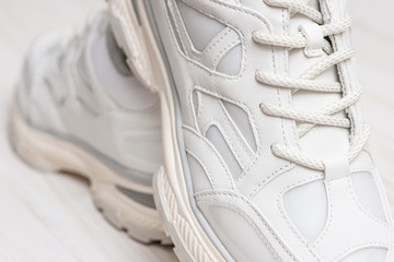 White sneakers with laces. A fragment of white shoes. New sneakers on white background. Fashionable sneakers