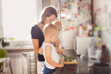 Obraz na płótnie Canvas Mom with baby help boy son chop broccoli