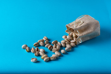  pistachios coming out of a sack with a blue background
