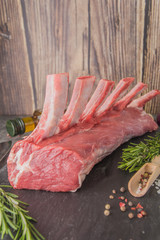 Raw beef rack on black slate with spices, side view