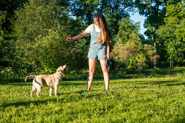 young attractive blond woman playing with her dog in green park at summer, lifestyle people concept