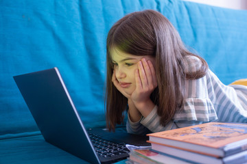 girl looking at laptop screen, doing homework for school, distance learning concept, e-learning