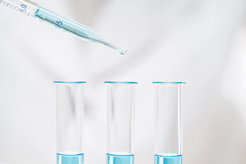 dripping light blue liquid into tube making coronavirus test in laboratory