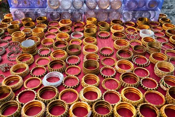 Obraz premium Beautiful golden colored Indian bangles arranged with care on a table to be sold at a street market, in the middle of the day, in Fort Kochi, India.