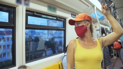 Woman travel caucasian ride at overground train airtrain with wearing protective medical red mask....