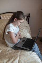 School girl studying online at home on the bed on the laptop. Stay at home. Coronovirus