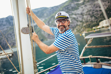 Mature man standing on the deck of his boat on a sunny afternoon.