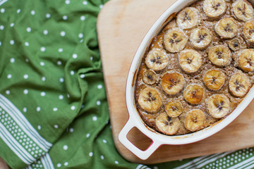 Tasty banana bread in a ceramic baking dish on a wooden cutting board