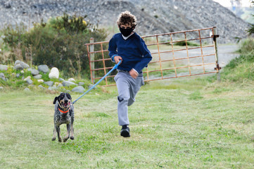 Coronavirus lockdown. Teenager with face mask takes his dog for a walk during coronavirus,running with pet. Quarantine in Mediterranean area, Italy, Spain, Cyprus. 