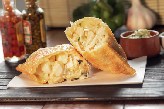 Pastel de bacalhau  brasileiro na mesa de um restaurante ou boteco ou bar com fundo decorado de piment&atilde;o alho e molho de pimenta