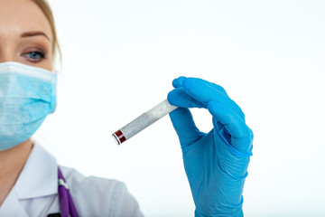 A blunted hand in a latex glove holds a blood test tube on a white background with place for text. Copy space. Female hand.