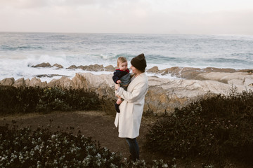 mother on a hike on the coast  while traveling with her baby daughter