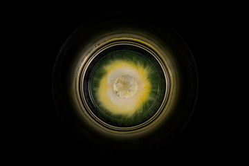 Gelbe Schokolinse löst sich im Wasserglas, optisch ähnlich einem Planeten im All.