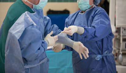 Doctor and nurse in hospital putting on personal protective gear PPE