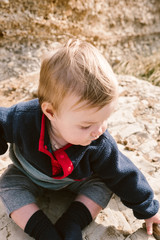 baby sitting on a rocky beach
