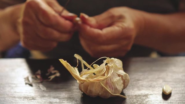 Hands of an old woman peeling garlic