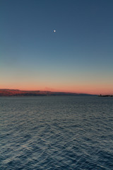 Strait of Messina at the sunset, with the moon and a lighthouse view from the Ferry