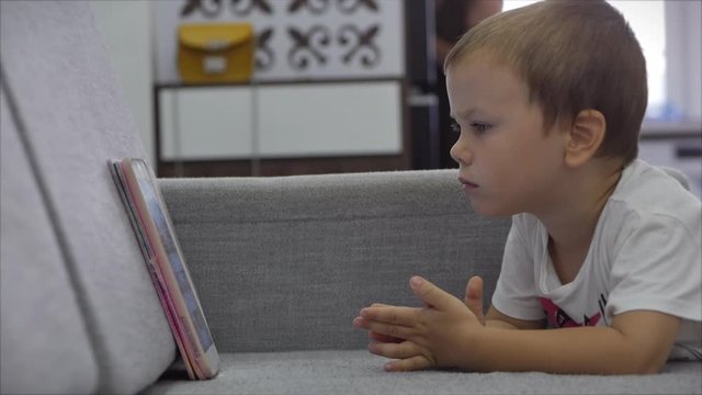 Small child hold pad computer surfing internet play game at home. Children tech addiction concept