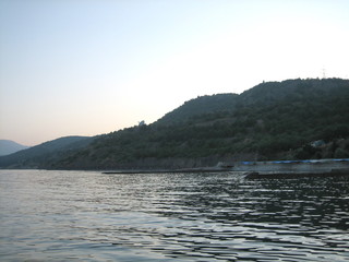 Rocky coast at sunset. In the distance, the coast mountains loomed in the mist.