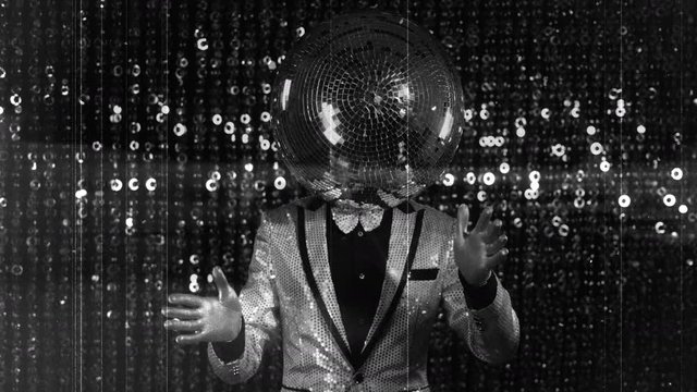 Man dancing with disco ball on head.