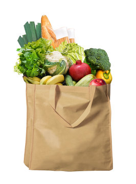 Eco friendly reusable shopping bag filled with bread, fruits and vegetables on a white background