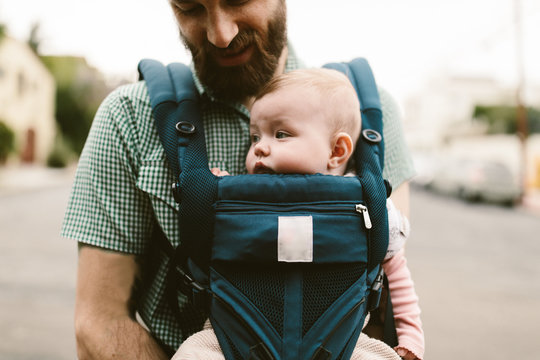 Baby girl being carried by her father in a carrier