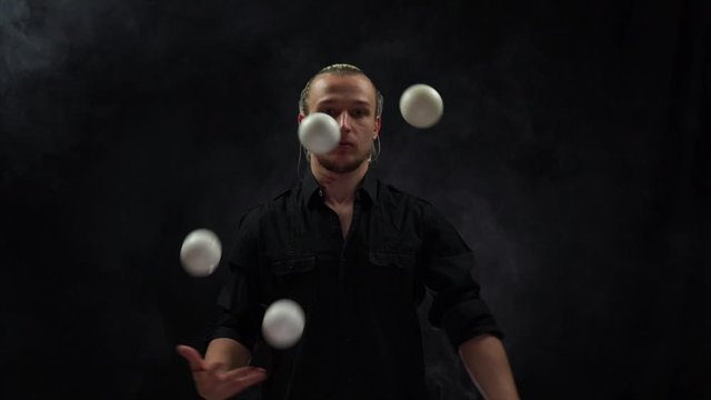 Man wearing a black juggling with white balls. Management, control and success
