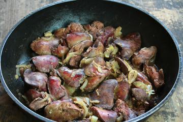 Fried livers with onions in a black pan