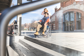 Young Couple on Wheelchair Trying to Go Down the Stairs.