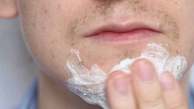 Man shaving with foam and manual razer. Close up of man shaving beard.