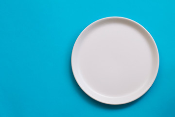 white empty plate on blue background, top view