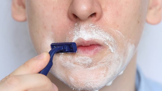 Man shaving with foam and manual razer. Close up of man shaving beard.