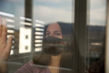 A young woman quarantined at home because of a virus pandemic outside
