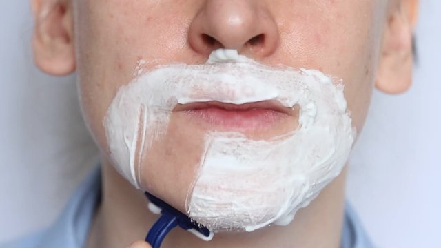 Man shaving with foam and manual razer. Close up of man shaving beard.