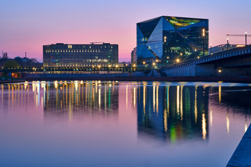 beautiful panoramic view at sunset, Berlin Spreebogen at Hugo-Preuss Bridge with a view of the Cube Berlin and John F. Kennedy House building at the main train station and the river Spree, purple sky - obrazy, fototapety, plakaty