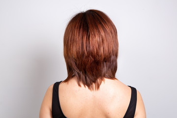 Smooth red-haired woman shot from behind, concept of hair care and physical appearance