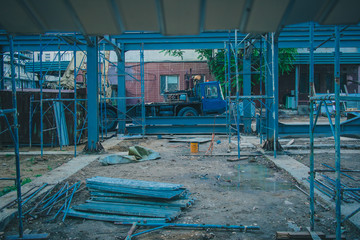 Construction site of a building with visible blue scaffolding towers and lift truck in the...