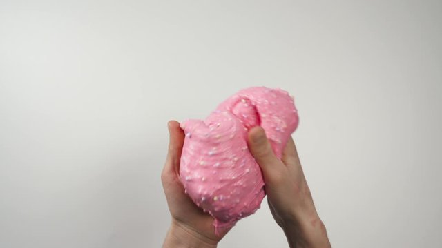 Hands playing with slime and hand wrap in slime by other hand, Close-up Top view. White background. Round colored blotches on the slime.