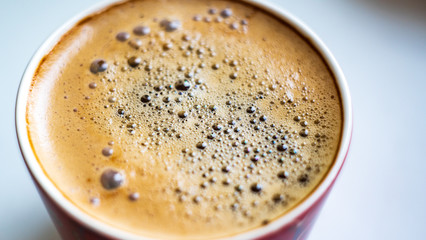 cup of coffee with bubbles on the surface fragment blurred background