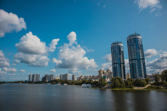 Panorama of Kiev and Dniprovski district waterfront, with the houses of ukrainian railways visible and Hydropark next to the Dniepr river or Rusanivska protoka in Ukraine on a warm summer day.