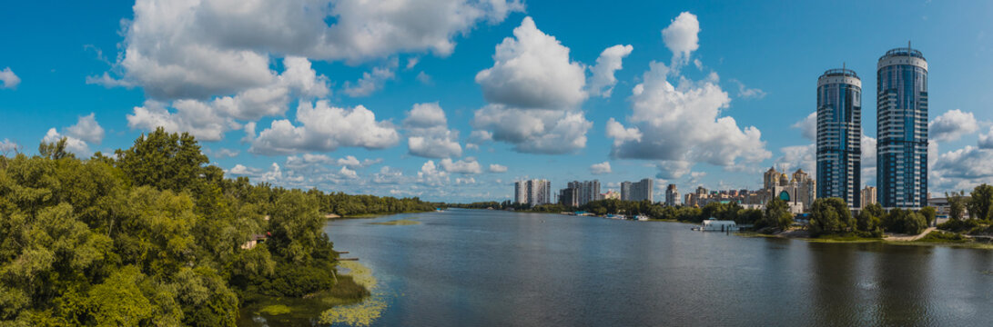 Panorama of Kiev and Dniprovski district waterfront, with the houses of ukrainian railways visible and Hydropark next to the Dniepr river or Rusanivska protoka in Ukraine on a warm summer day.