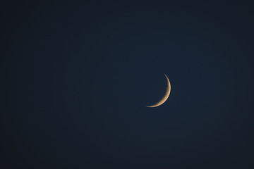 Obraz na płótnie Canvas Thin yellow crescent moon on a dark blue background