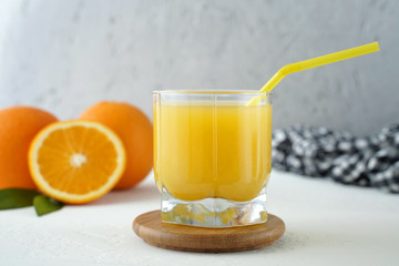 glass of freshly squeezed orange juice and oranges on the table, close-up